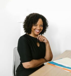 Happy woman sitting at a desk in a bright modern office, smiling confidently.